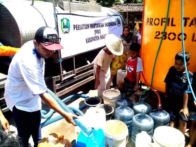 Norik, Ketua PWI Kabupaten Magetan Mengisi Air Bersih Pada Ember dan Jerigen Milik Warga Desa Kuwon, Kecamatan Karas. ( Norik/Magetan Today)