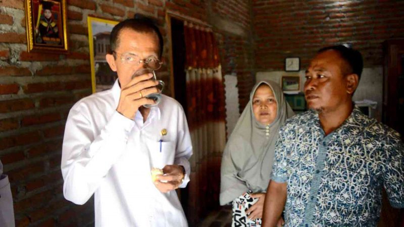 Bupati Magetan, Suprawoto, Menikmati Segelas  Air Putih Yang Disajikan Pemilik Rumah Penerima Bantuan RTLH. ( Norik/ Magetan Today)